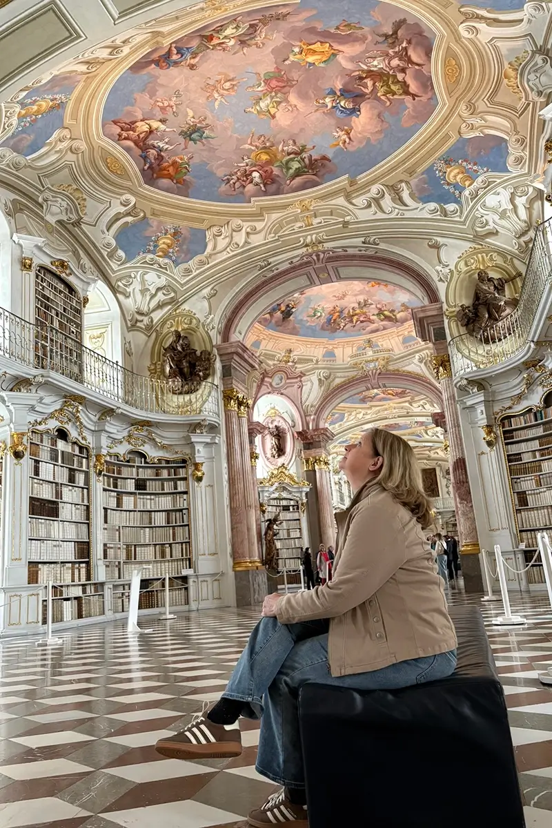 Tammy founder of Wanderlustria and the Austria Wanderlust Website sitting in the Admont Abbey Library